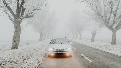 A car travels down a lonely, snowy country road
