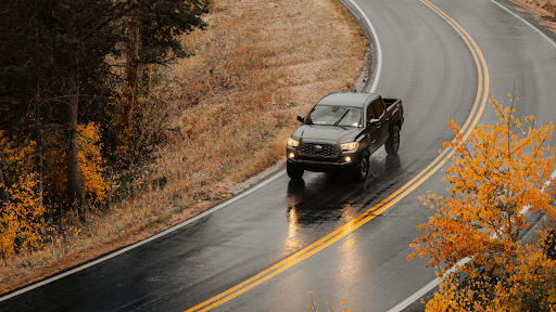 A truck drives around a curve on a slick road in fall.