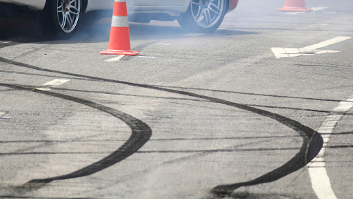 A car with smoke from braking abruptly and tread marks on a test track.