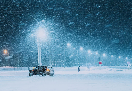 a person walking away from their car in a snowstorm