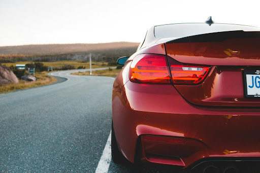 the rear bumper of a red car on an empty winding road