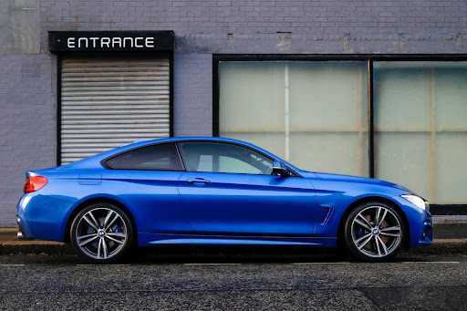 a blue car outside of a building’s entrance
