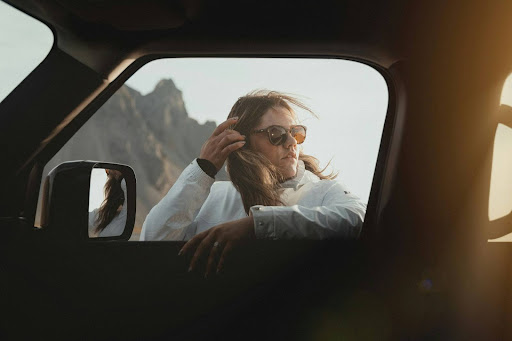 a woman leaning against a vehicle’s passenger side