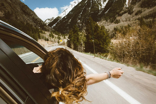 a woman riding passenger in a car with her head out the window