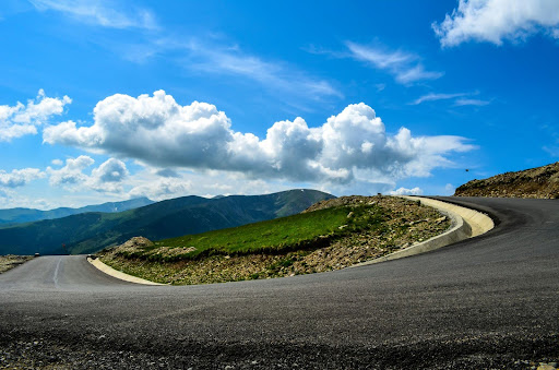 Winding mountain road under a blue sky, designed for smooth and controlled driving.