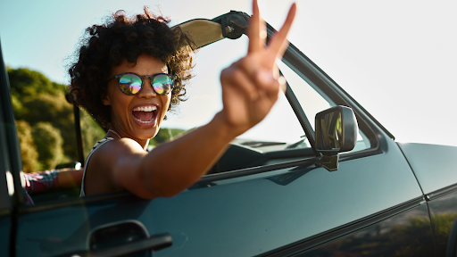 Smiling woman in a convertible, enjoying a smooth and comfortable ride on all-season tires.