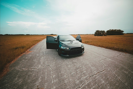 Black sports car with open doors parked on an open road, ready for the next journey.