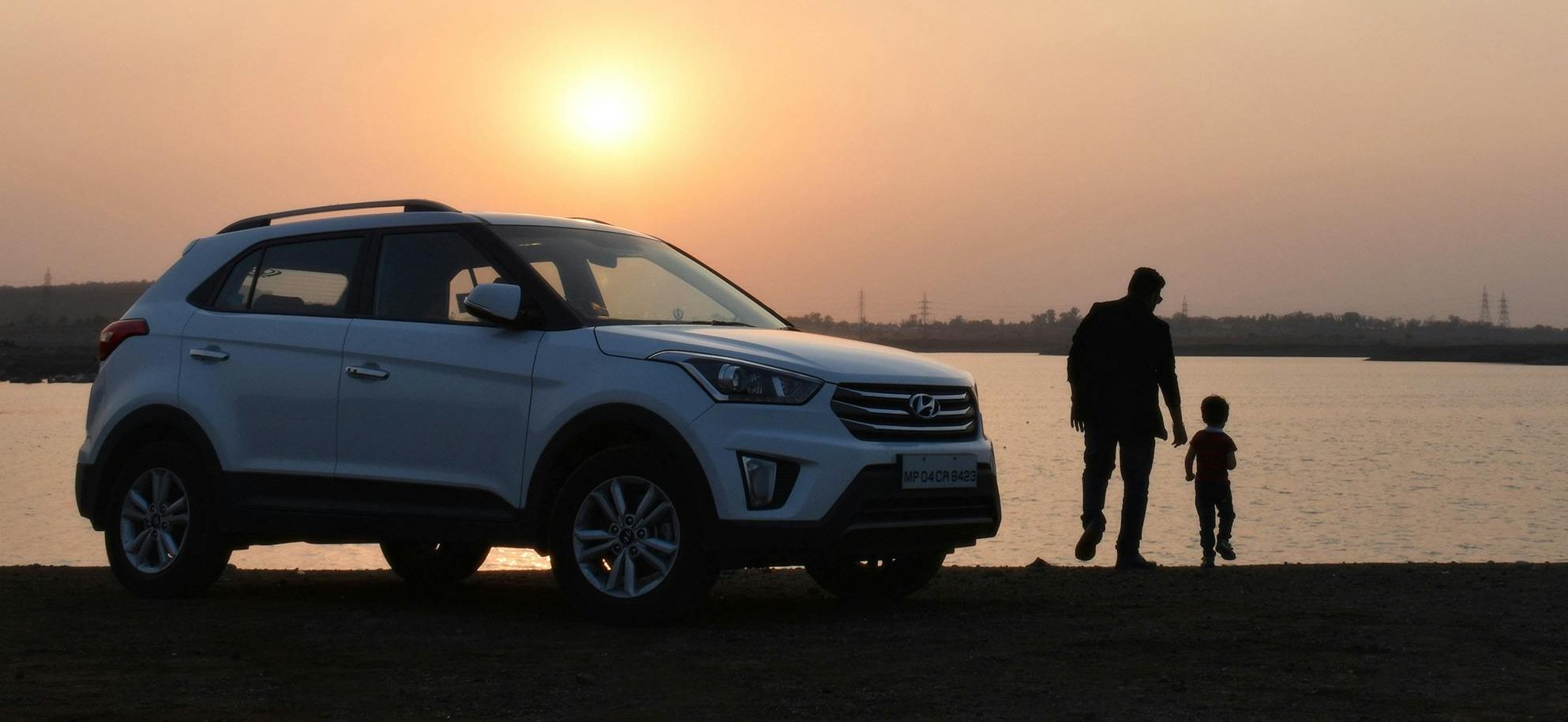 dad with son on the beach with SUV vehicle